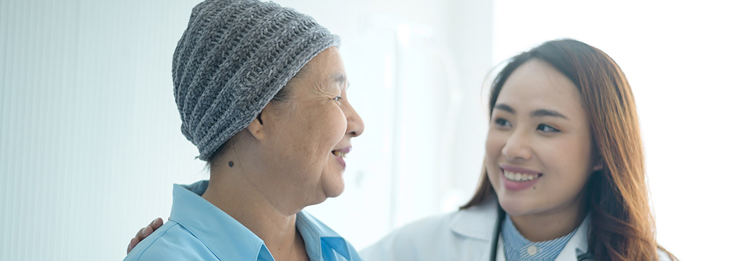 Doctor smiling at elderly patient, conveying care in brain tumor therapy.